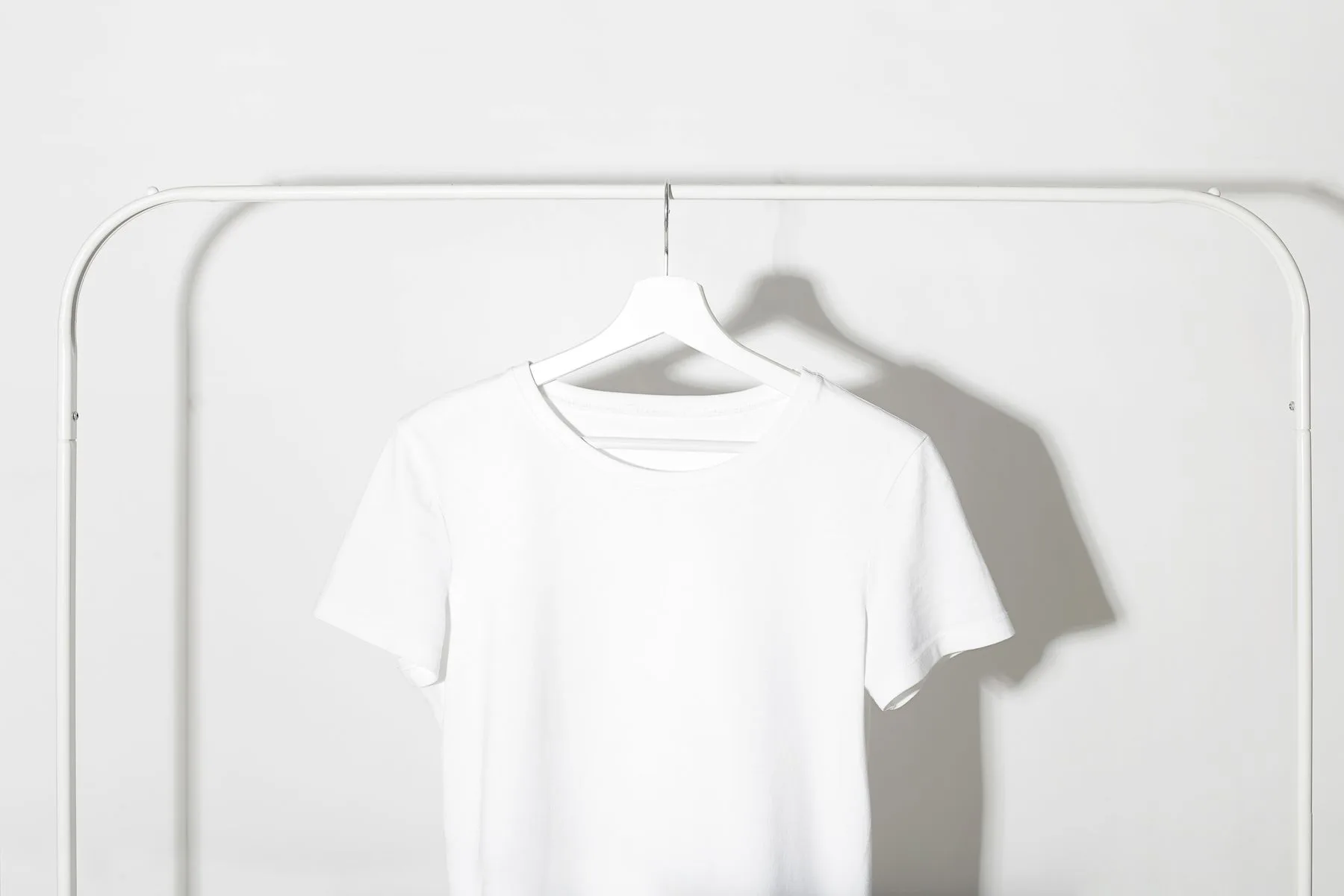 Camiseta branca lisa pendurada em uma estrutura minimalista