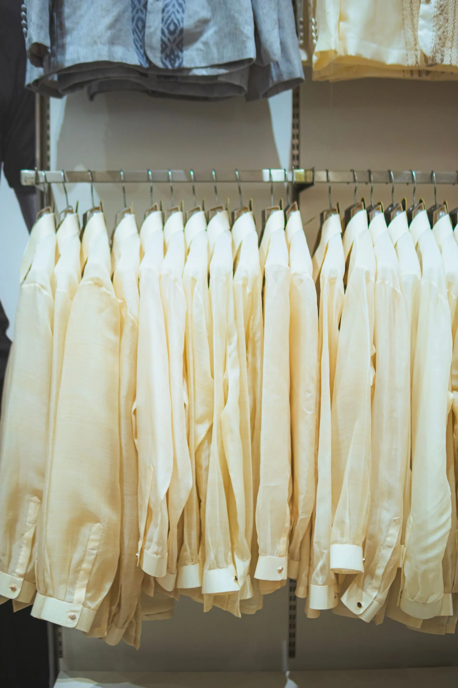 Arara contemporânea com peças neutras de uniforme penduradas em uma exposição limpa